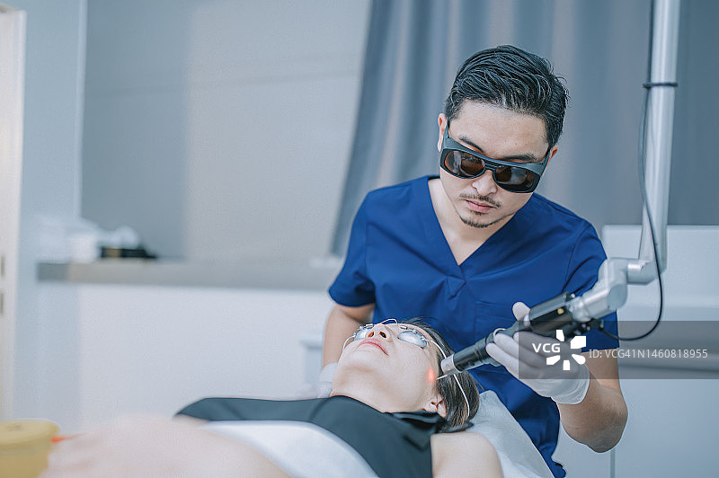 中国男美容师在诊所为女顾客进行激光IPL治疗图片素材