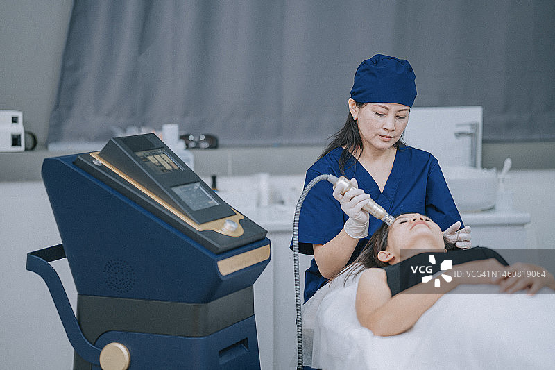 华裔女性美容师为顾客进行微晶磨皮图片素材
