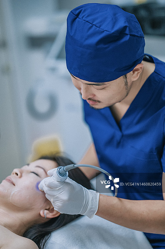 男美容师为女顾客做微晶换肤护理图片素材