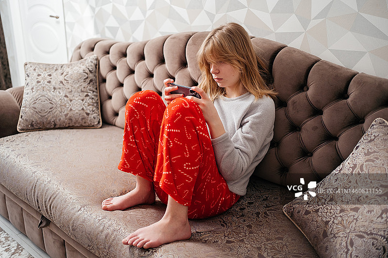 在沙发上玩智能手机的少女图片素材