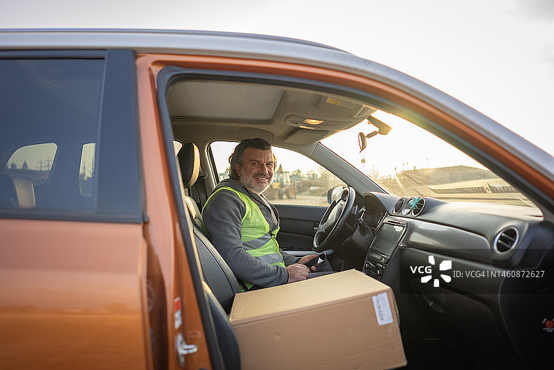 快递员在货车里准备送货，看着镜头图片素材