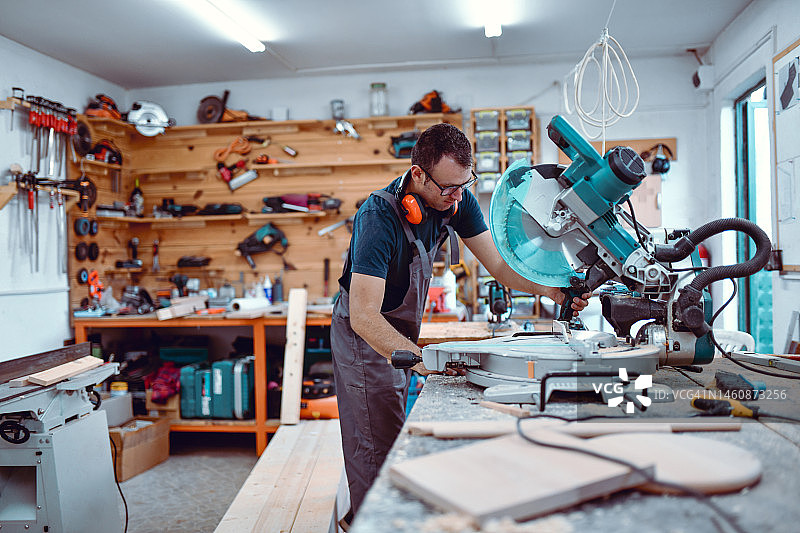 木匠小心地使用大型圆锯切割所需的木板形状图片素材