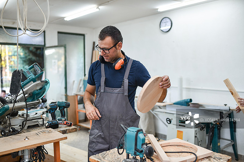 对圆形座椅形状感到满意的男木匠图片素材