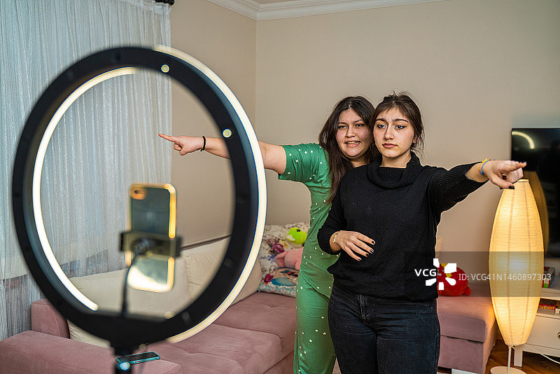 在家拍摄视频并对着环形灯跳舞的少女肖像，年轻博主概念图片素材