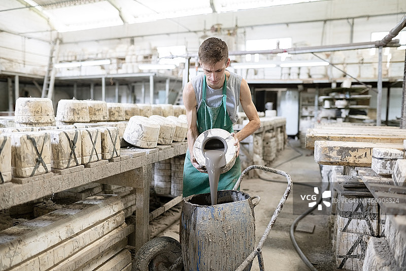 年轻女子在陶瓷厂将泥浆从模具倒入罐中图片素材