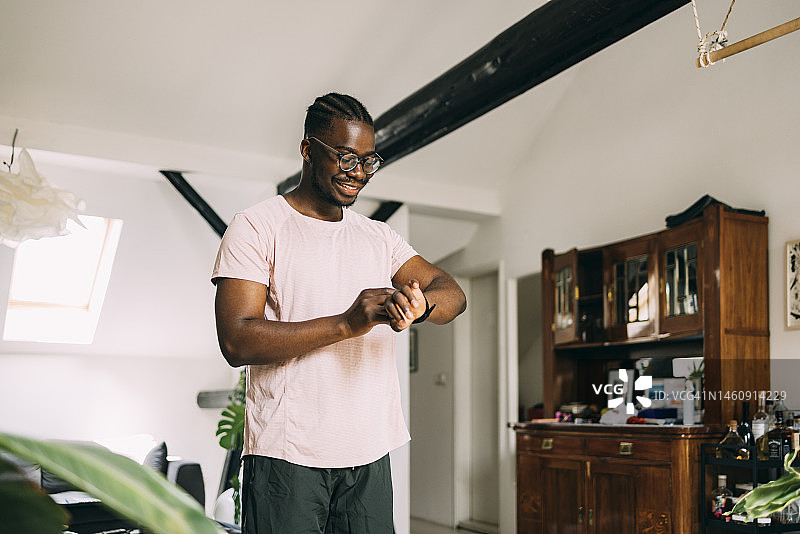 一位戴眼镜的快乐男子在他的客厅里等候某人图片素材