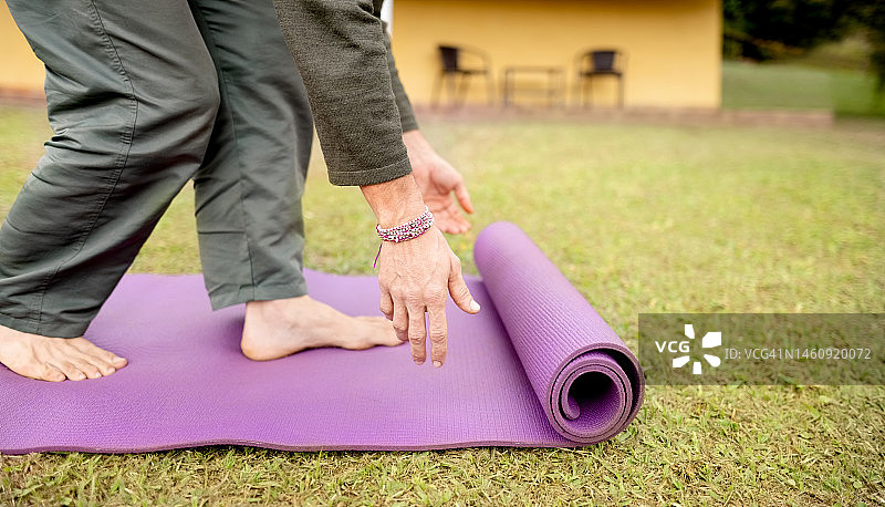 男人在户外草地上展开瑜伽垫的特写图片素材