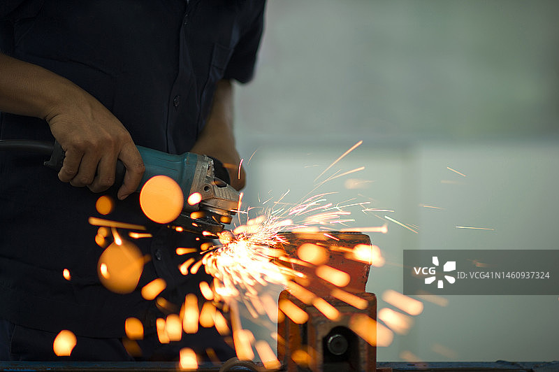 男人用砂轮机打磨钢铁，火花四溅图片素材