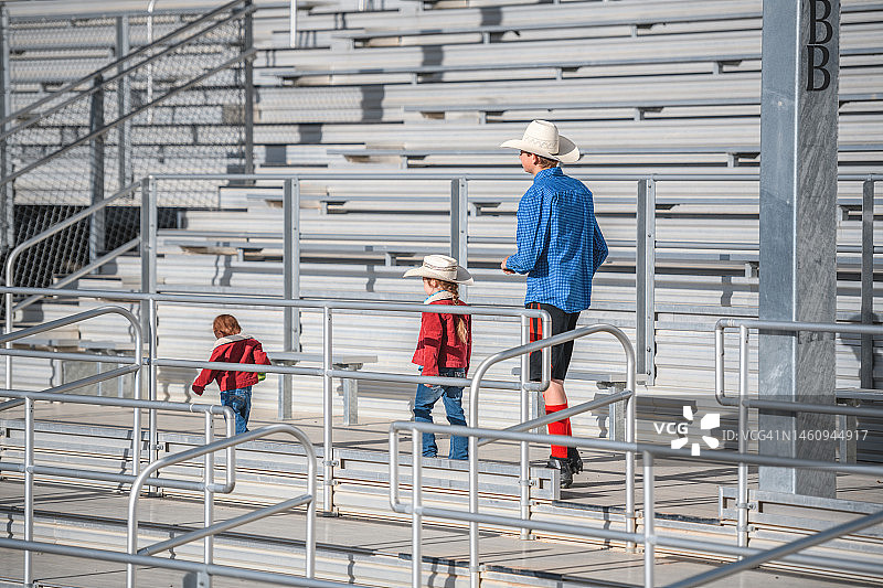 牛仔带着两个孩子走在竞技场的看台上图片素材