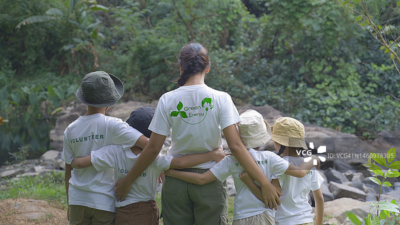 亚洲志愿者和儿童的背影，衬衫上印有绿色能源标志图片素材