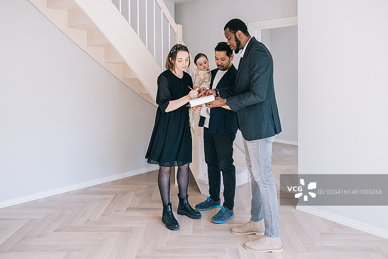 年轻家庭与房地产经纪人签订合同图片素材