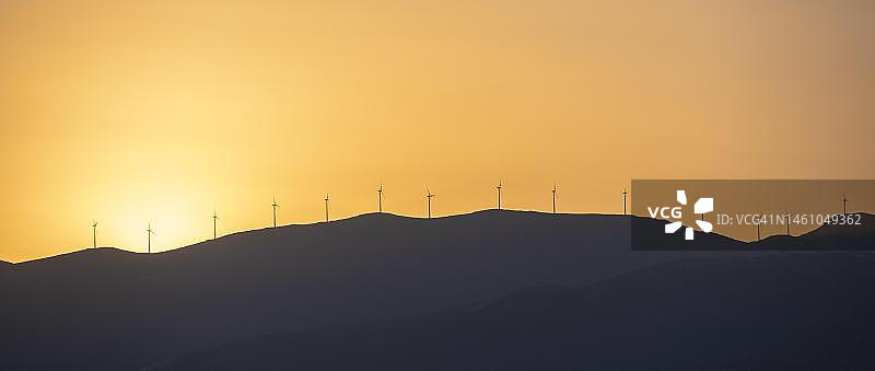 希腊伯罗奔尼撒半岛日落时分的地平线上的风力涡轮机图片素材