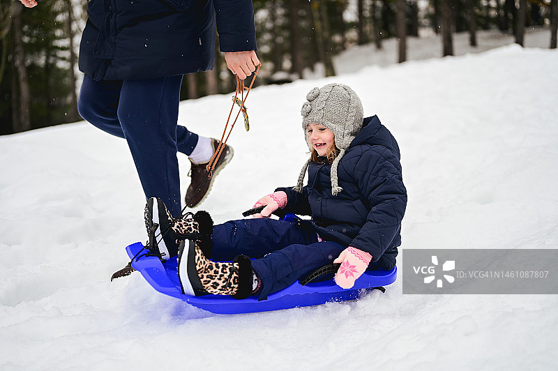 父亲用雪橇带着小女儿滑雪图片素材