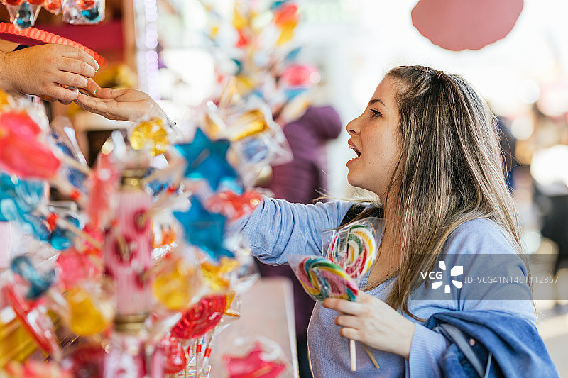 年轻女人在集市糖果店购买彩色冰棒图片素材