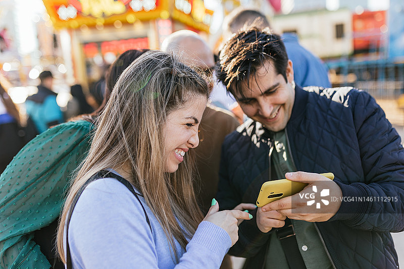 男人在春日集市上向朋友们展示手机照片图片素材