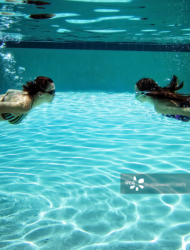 母亲和小女儿在游泳池里享受水下夏日乐趣图片素材