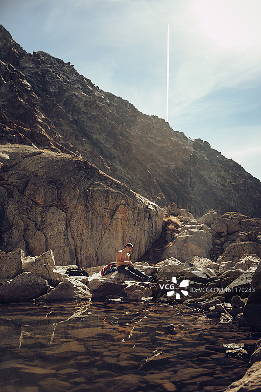 赤膊男子在山顶的清水湖边休息图片素材