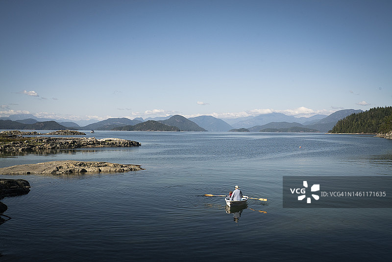 爷爷和孙子在宽阔的水道上划着白色划艇图片素材