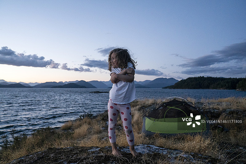 年轻女孩在黄昏时分于草岛上露营图片素材