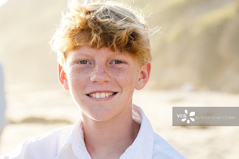 在海滩上微笑的红发雀斑少年图片素材