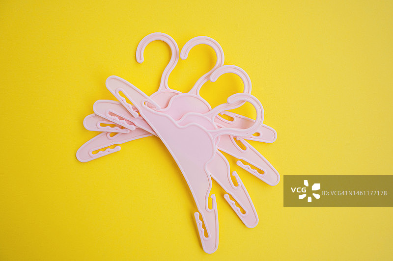 黄色背景上的粉色衣架平铺图：时尚、风格和购物概念图片素材