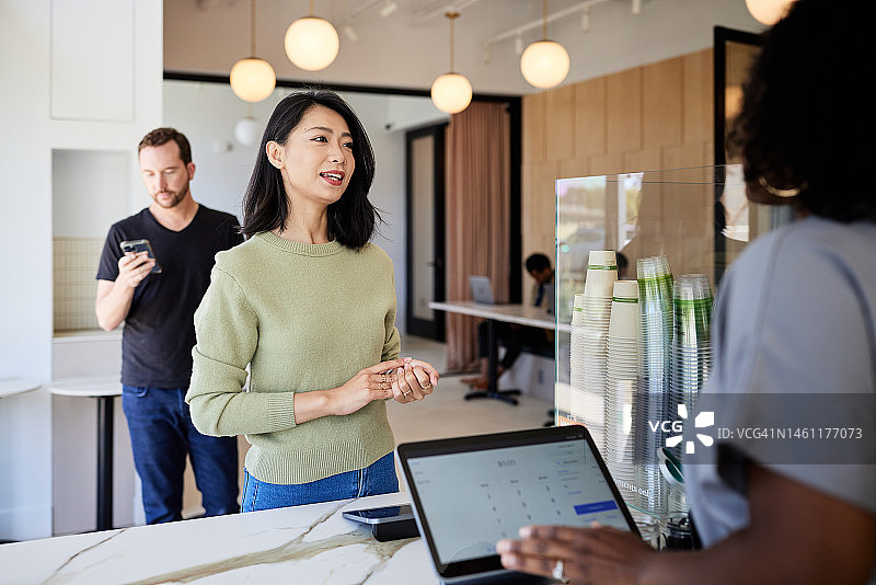 在咖啡店结账柜台，女顾客正在下单图片素材