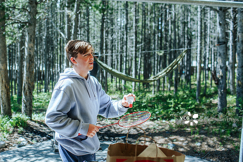 在森林外拿着羽毛球套装的少年图片素材