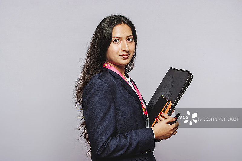 灰色背景下手持书本的印度年轻女孩图片素材