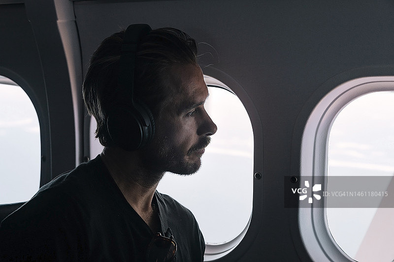 男人在飞机上戴耳机听音乐图片素材
