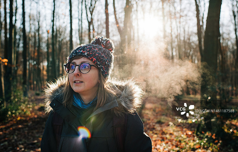 日出时分在寒冷空气中戴帽子和眼镜的女人图片素材