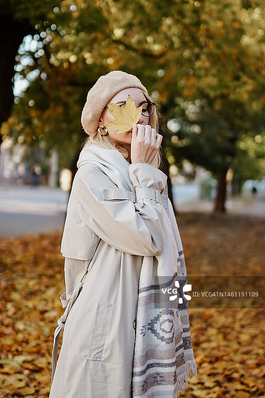 穿着秋装的女孩用枫叶遮住脸图片素材