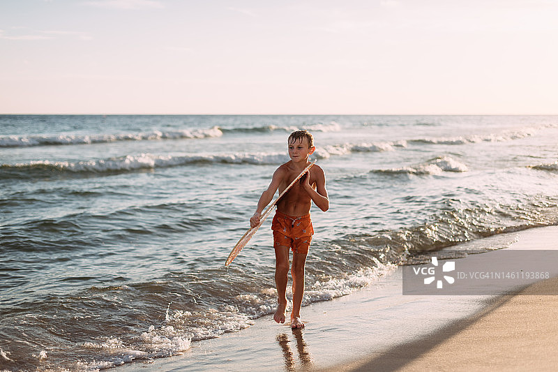 男孩带着滑板沿岸行走图片素材