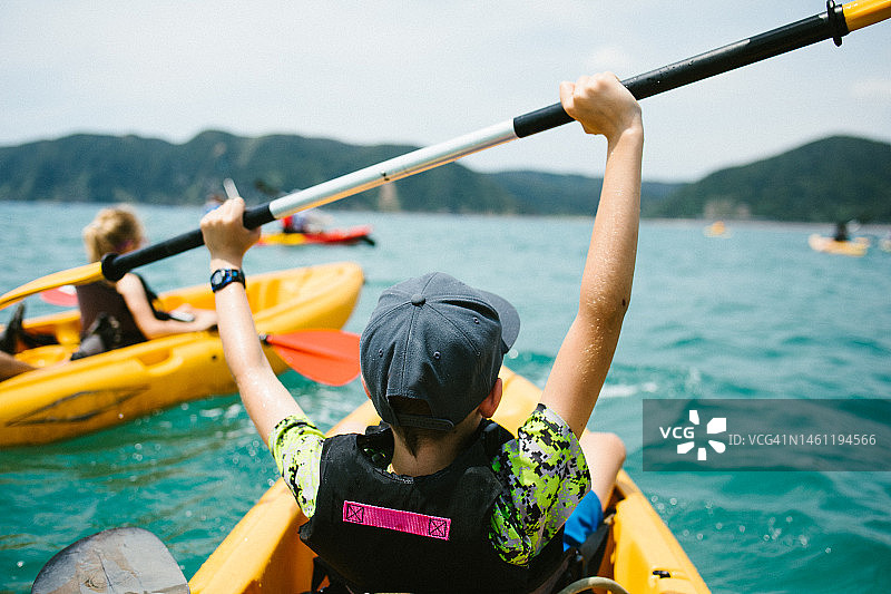 和家人一起参加海洋探险，坐在皮划艇上的兴奋男孩图片素材