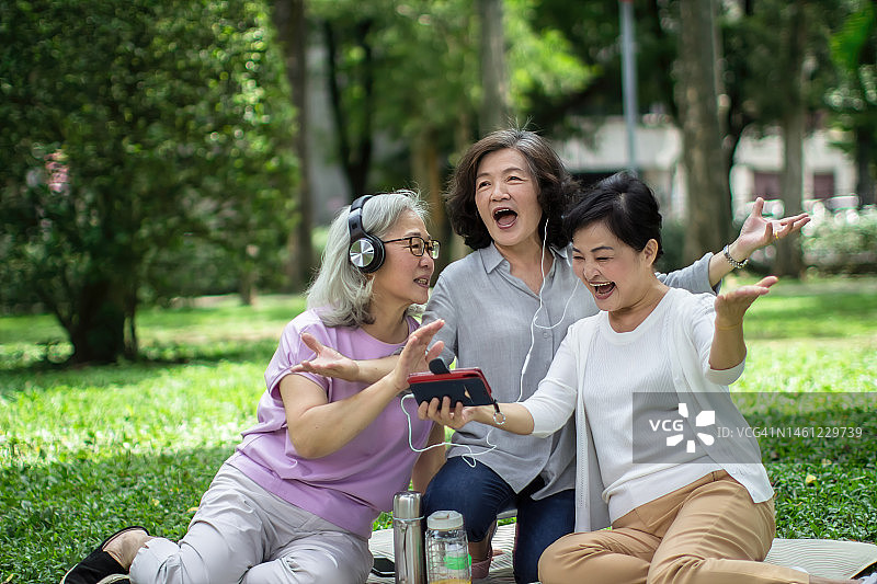 快乐的老年妇女在智能手机上欣赏视频图片素材