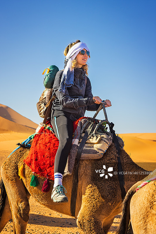 女游客在摩洛哥梅尔祖卡沙漠骑骆驼图片素材