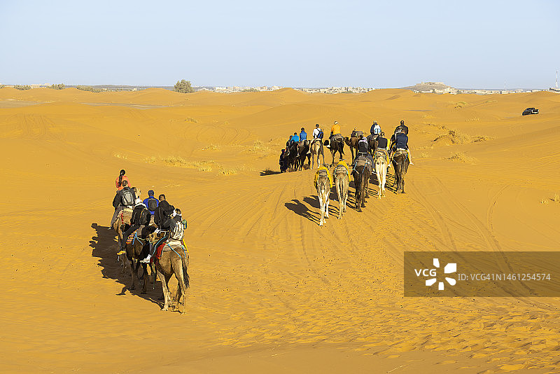 游客在摩洛哥撒哈拉沙漠Erg Chebbi的梅尔祖卡骑骆驼图片素材