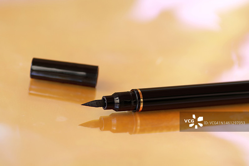 黑色眼线在彩色背景上的特写，化妆品与美容行业概念图片素材