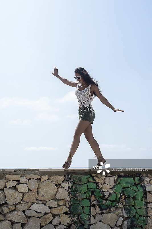 无忧无虑的棕发女子在海边墙上跳舞图片素材