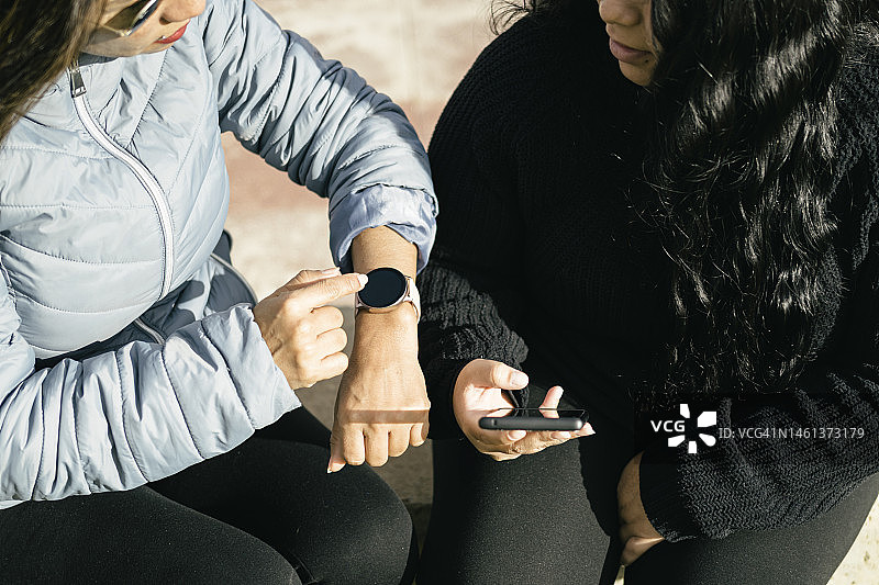 两个年轻漂亮的女孩在用智能手机发短信和聊天图片素材