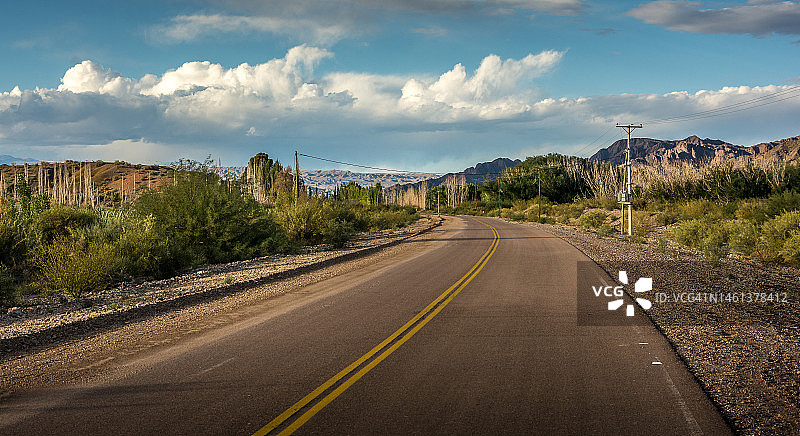 阿根廷圣胡安卡林加斯塔的树木和天空之间的空旷道路图片素材