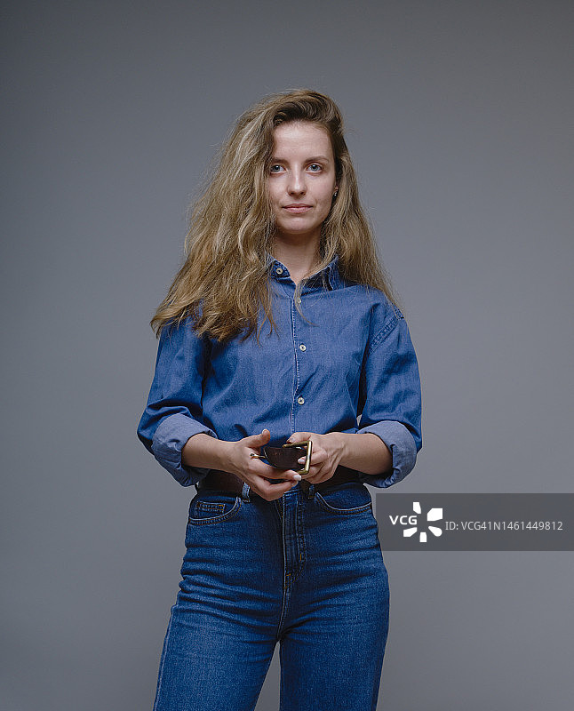 споконая женщина в джинсовом костюме держит ее пояс图片素材