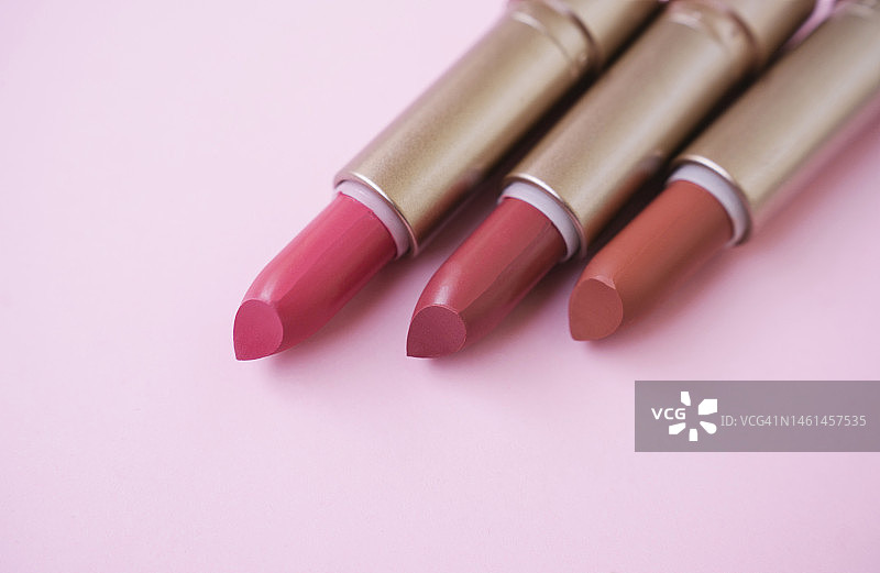 粉色背景上不同色调的红色和粉色口红，美容产品图片素材