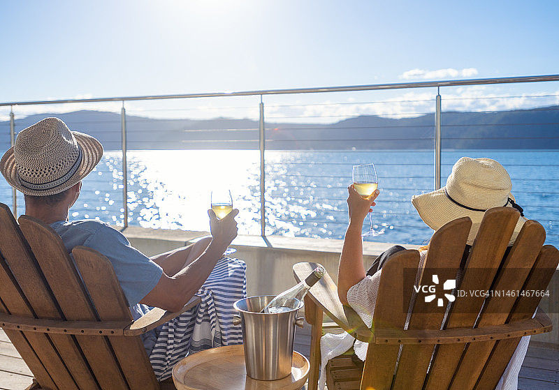 情侣在水上小屋的躺椅上放松并品酒图片素材