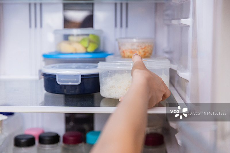 亚洲女人将剩菜放入冰箱图片素材