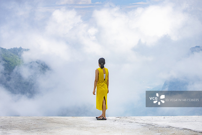 欣赏云雾缭绕高山自然风光的亚洲游客图片素材