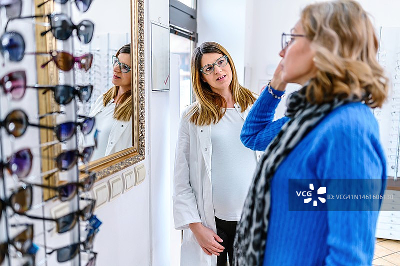 女人在商店挑选眼镜，店员提供帮助图片素材