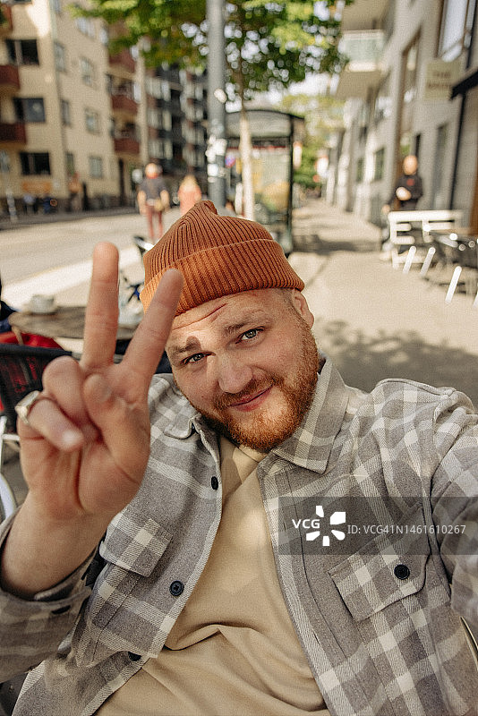 微笑男人自拍并展示和平手势图片素材