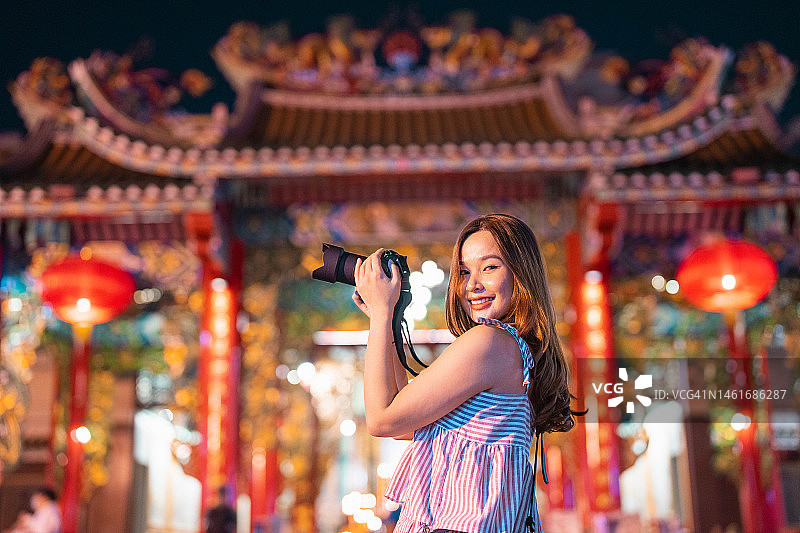 在唐人街拍摄中国新年灯笼装饰的年轻亚裔女子（低角度拍摄）图片素材