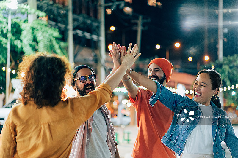 多民族朋友在夜晚的街道上击掌图片素材