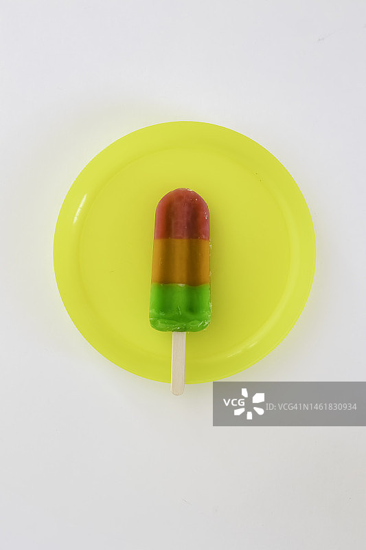 黄色盘子里的彩虹冰棒图片素材